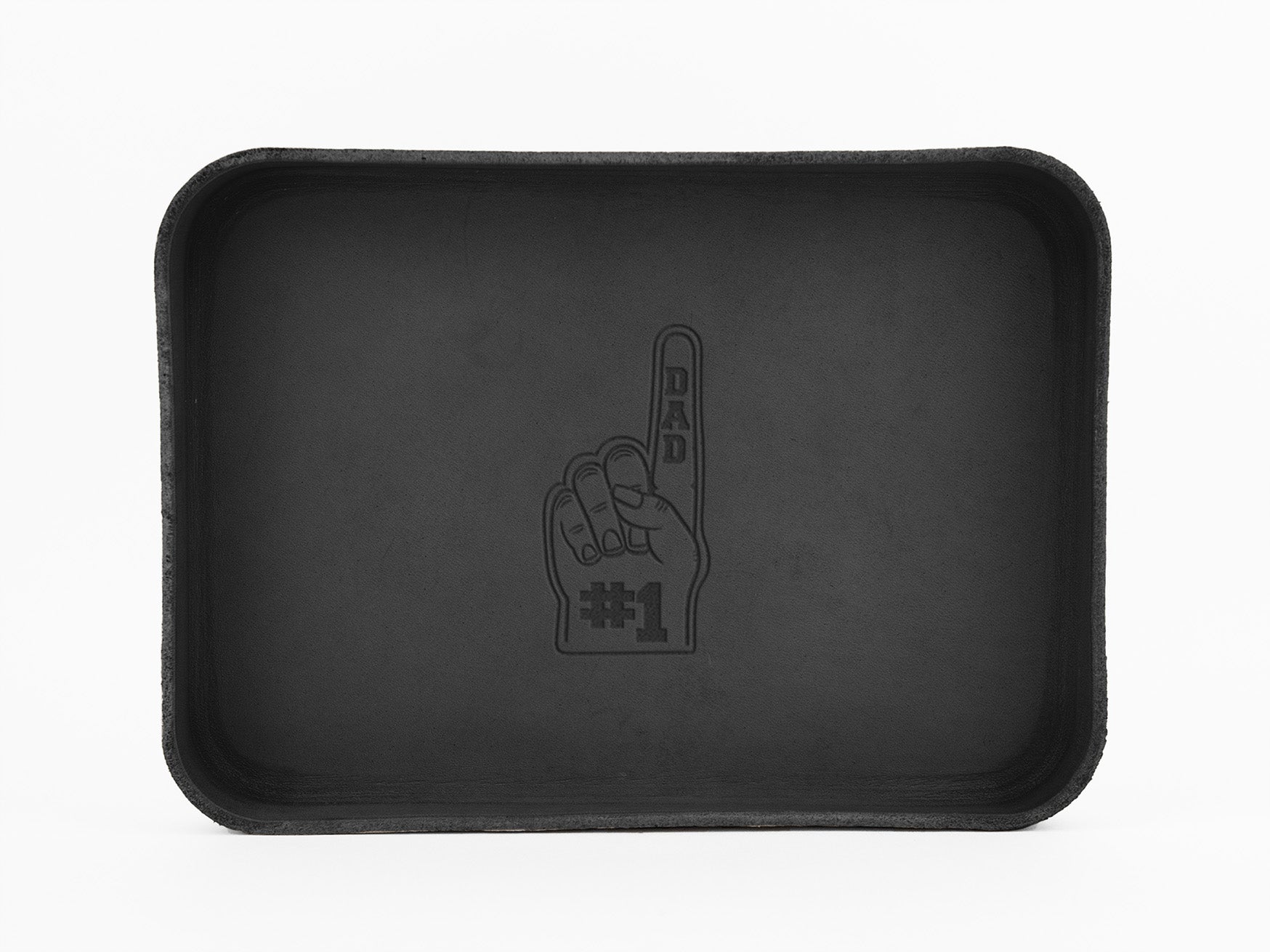 A black rectangular tray with an illustration of a hand holding up one finger, labeled “DAD #1” in the center. The tray has a simple, minimalist design and a textured edge.