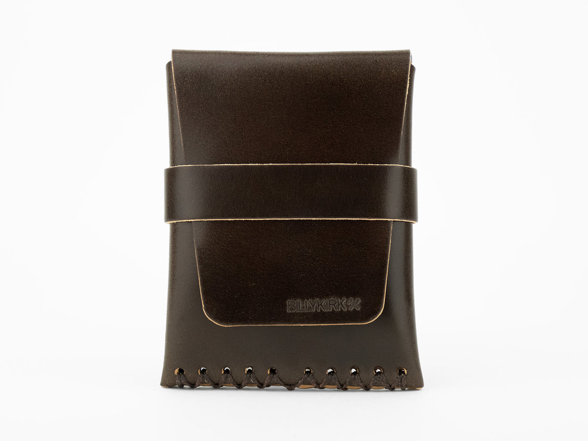 A dark brown leather pouch with visible stitching at the bottom and a horizontal strap across the front, displayed upright on a white background. The word BLVKRVK is embossed on the front flap.