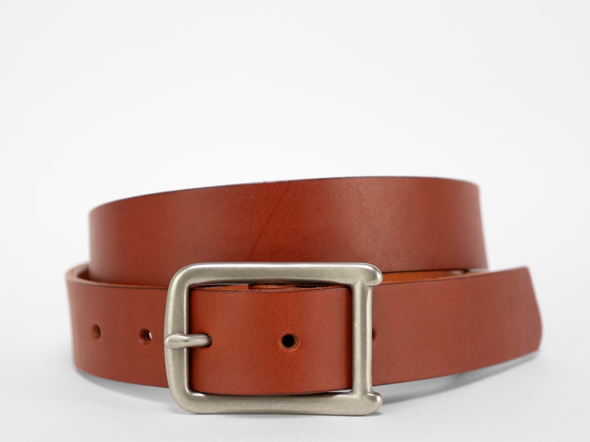 A brown leather belt with a silver rectangular buckle is coiled on a plain white background.