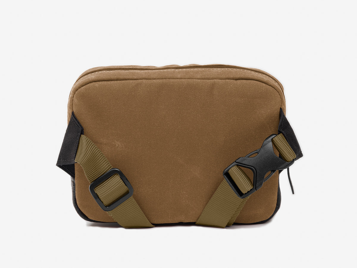 Back view of a small brush brown waxed canvas crossbody bag with adjustable strap.