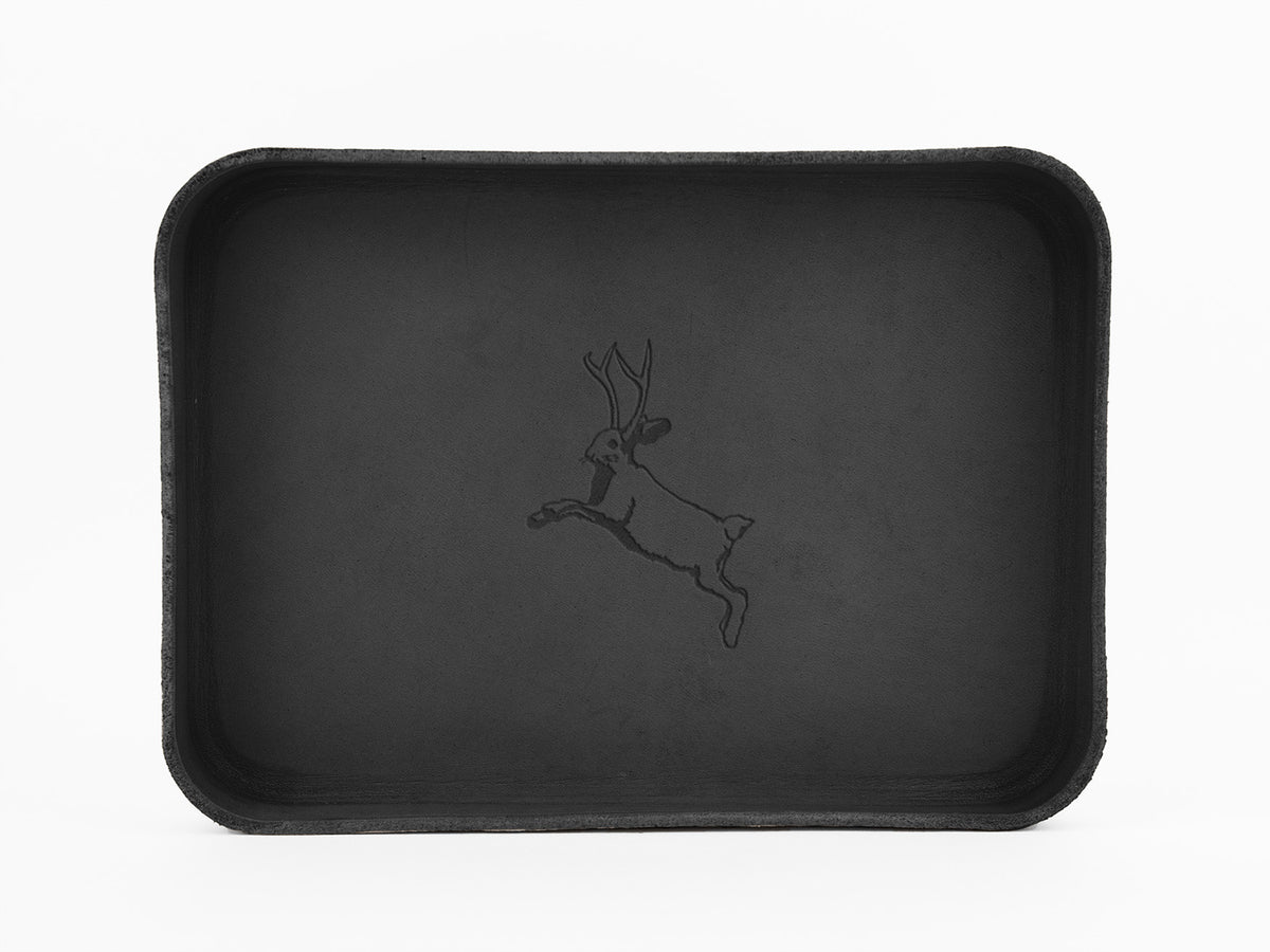 A rectangular black tray with rounded corners features an outline illustration of a leaping jackalope, a mythical animal with antlers, in the center. The background is plain white.