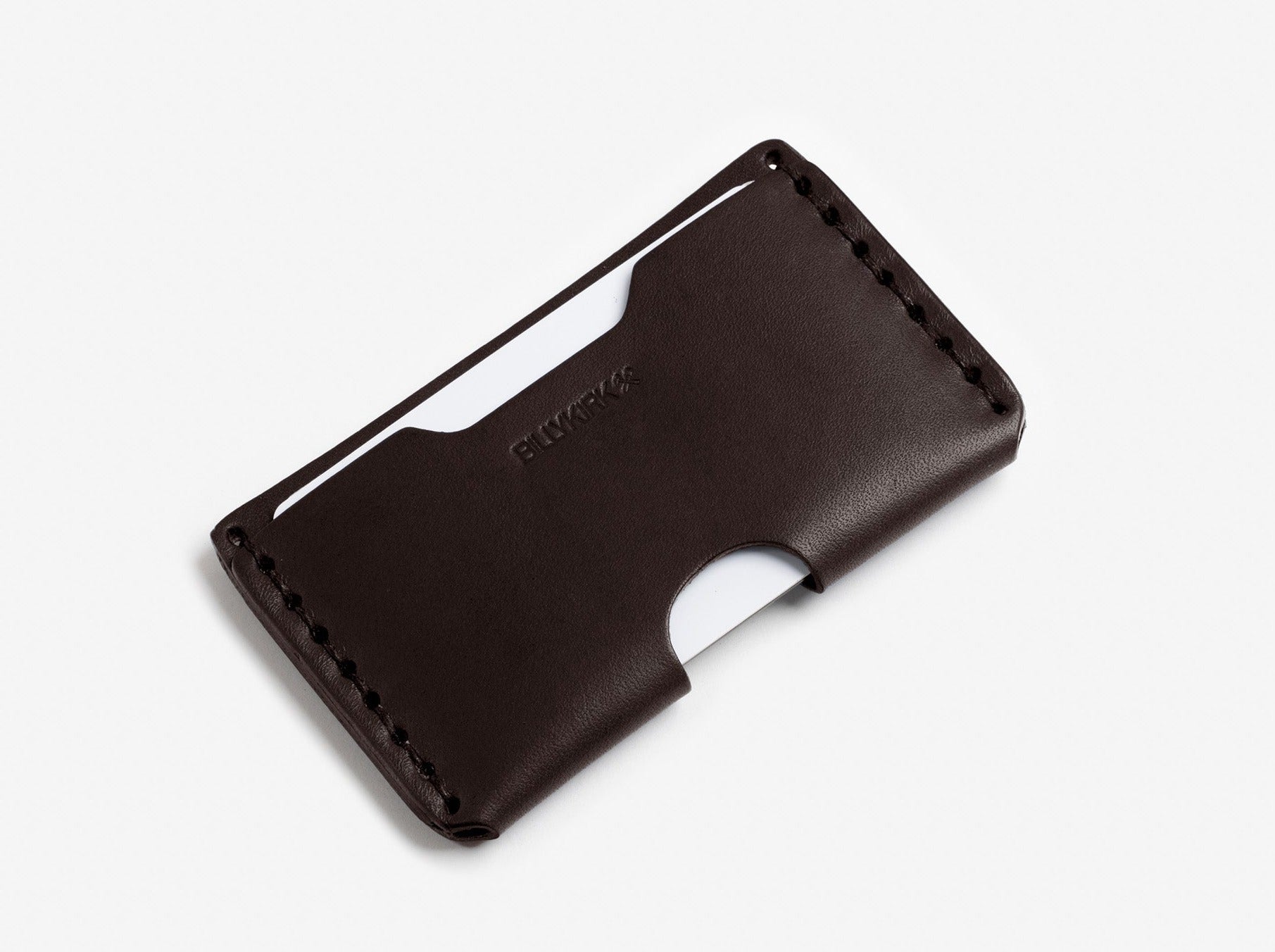 A dark brown leather wallet with visible stitching along the edges, holding two white cards, and featuring a small curved cutout on one side.