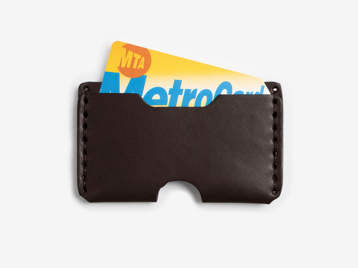 A black leather card holder with an MTA MetroCard partially visible inside, set against a white background.