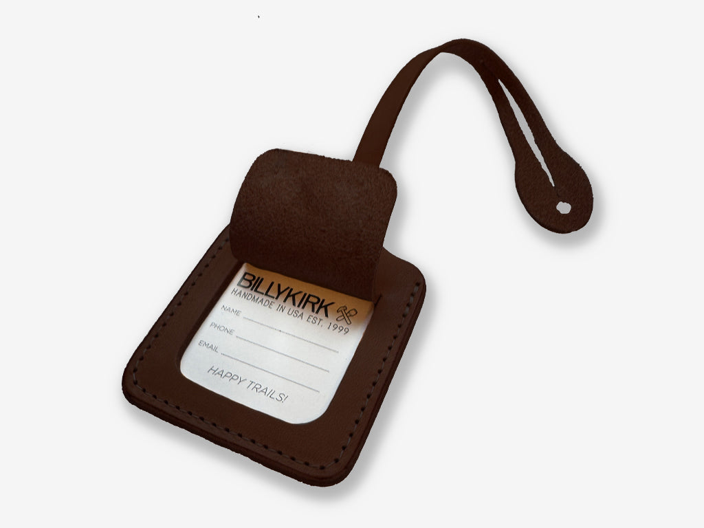 Brown leather luggage tag with a label on a white background
