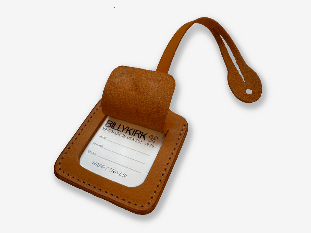 Brown leather luggage tag with a white label on a light gray background