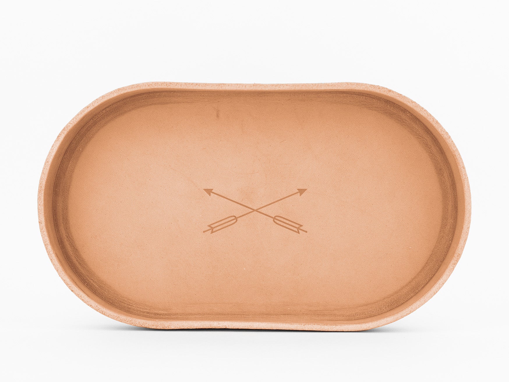 An empty, oval-shaped, natural colored  tray with two intersecting arrows engraved in the center, shown on a white background.