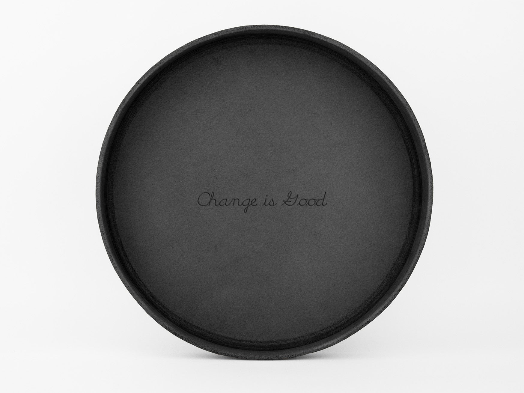 A round, black tray with the words “Change is Good.” written in the center, placed against a plain white background.