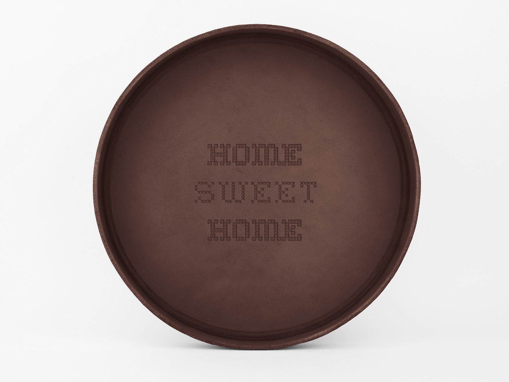 A round brown tray with the words HOME SWEET HOME engraved in a dotted pattern in the center. The background is plain white.