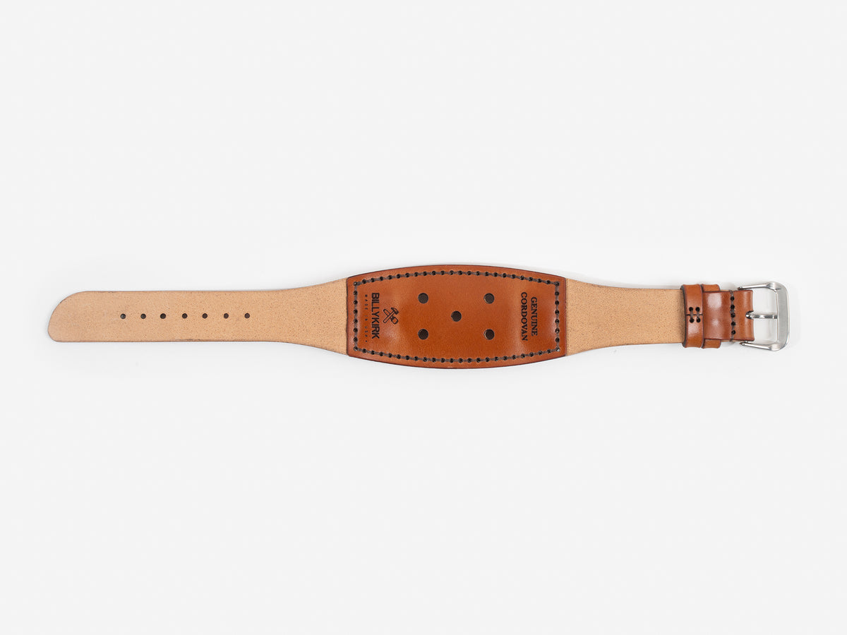 A wide, tan cordovan leather watch strap with black stitching, adjustment holes, a silver buckle, and the brand name BILLYKIRK embossed on it.