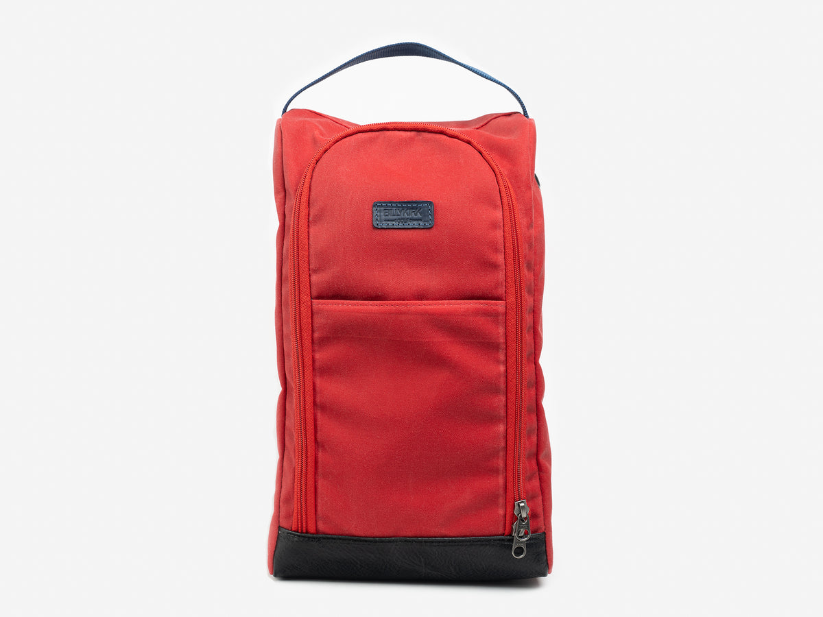 A red fabric shoe bag with a black handle on top, a front zipper pocket, and a black base, displayed against a plain light background.