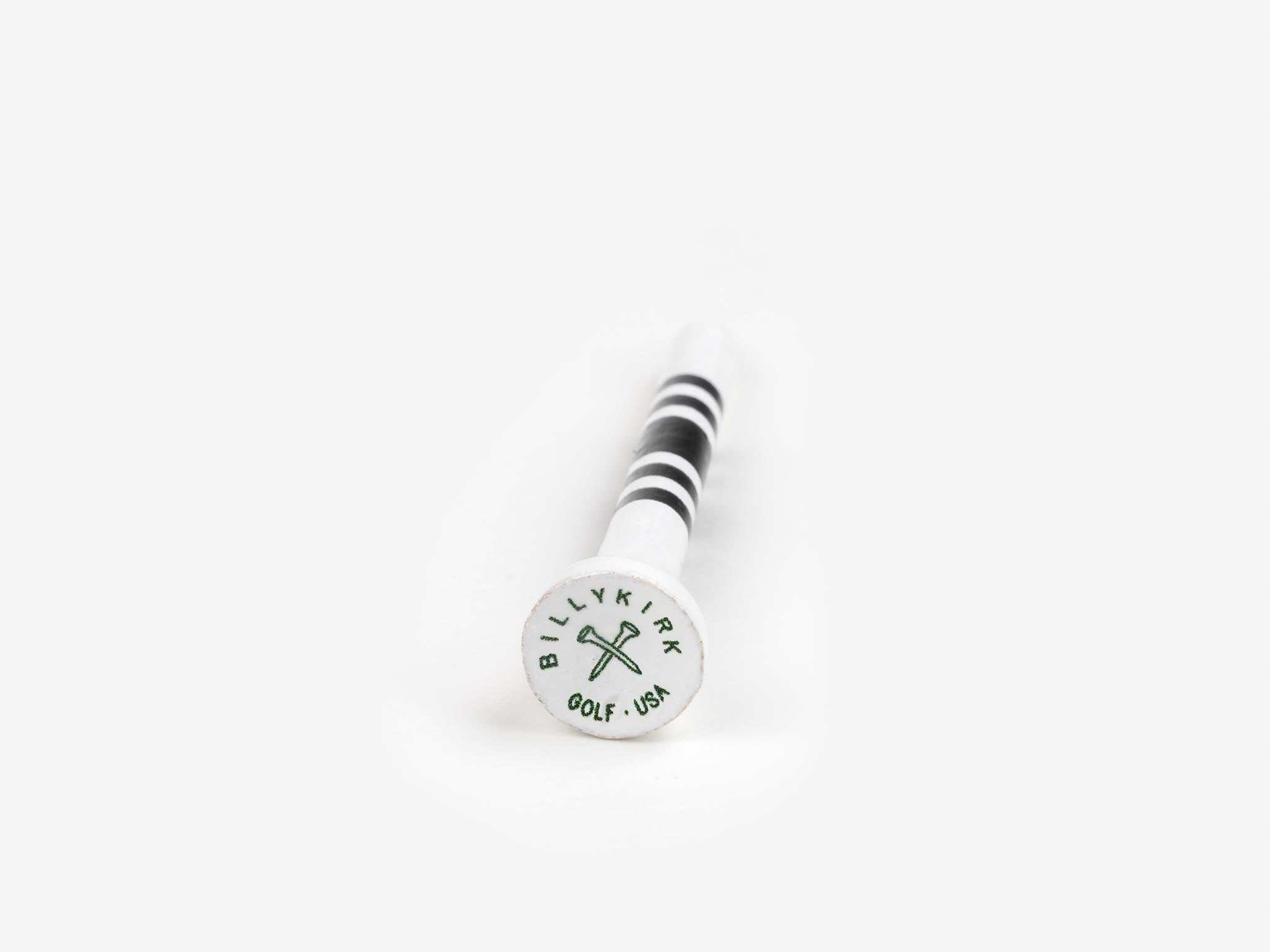 A white golf tee with black stripes, lying on a white surface. The top of the tee displays the text “BILLYKIRK GOLF USA” surrounding two crossed golf clubs.