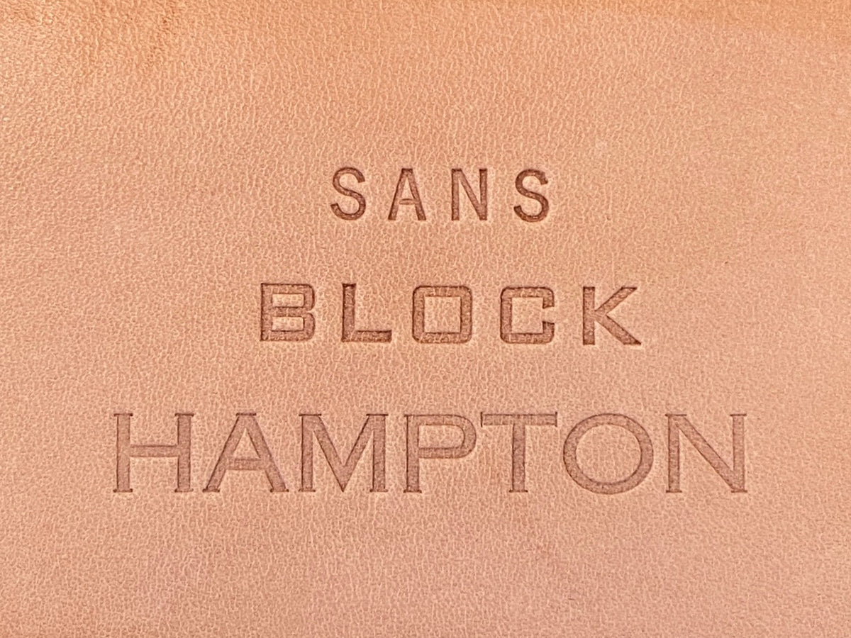 Embossed leather with the words SANS BLOCK HAMPTON in three different font styles and sizes.