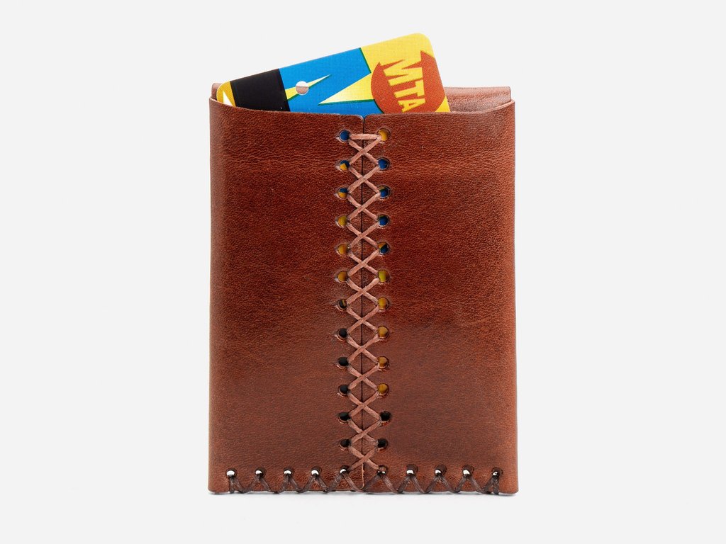 A brown leather wallet with decorative stitching down the center holds a colorful card partially visible at the top. The background is plain white.