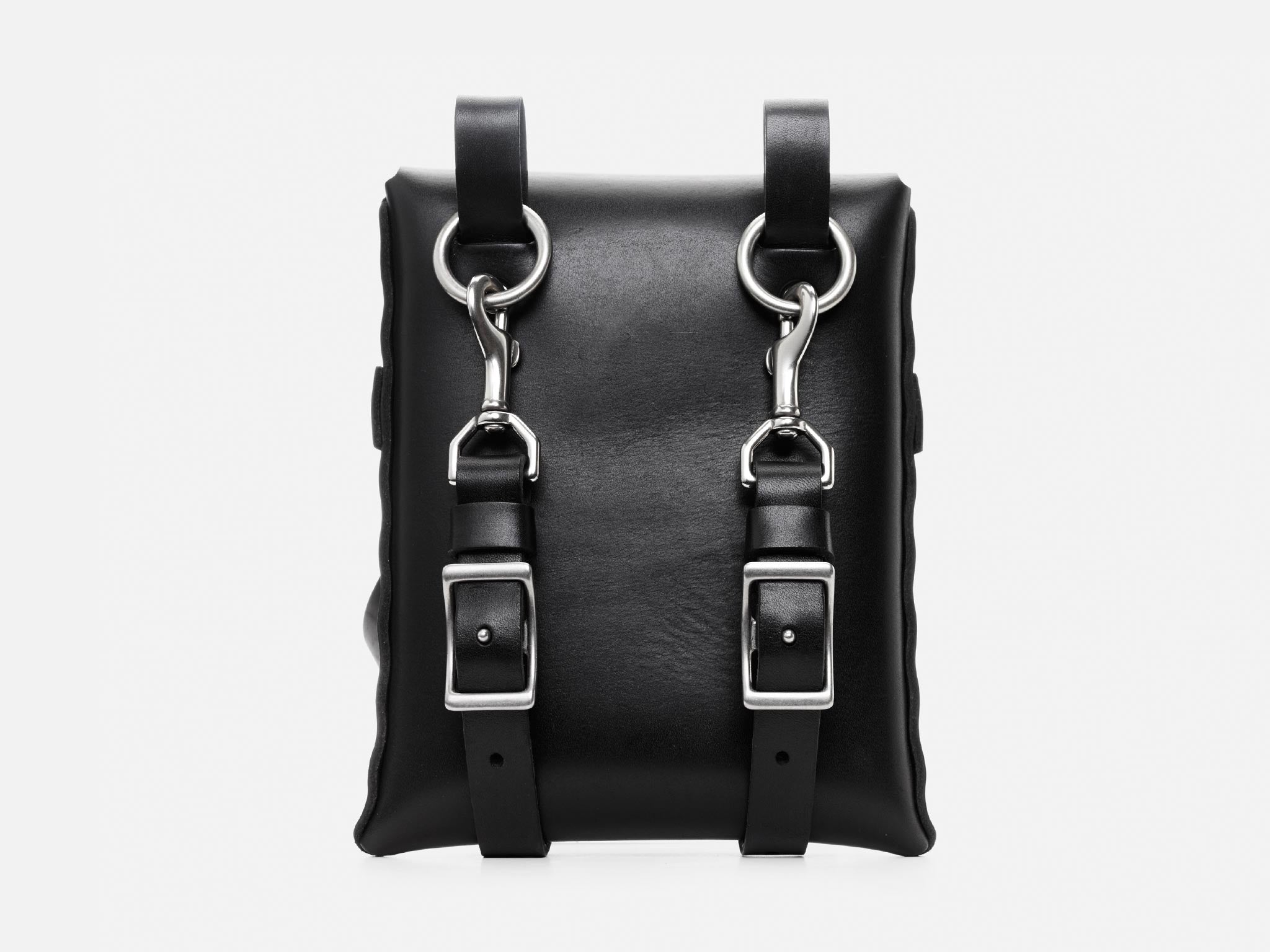 A black leather bag with two silver buckles and metal clasps on the front, featuring vertical straps and a clean, minimalist design against a plain white background.