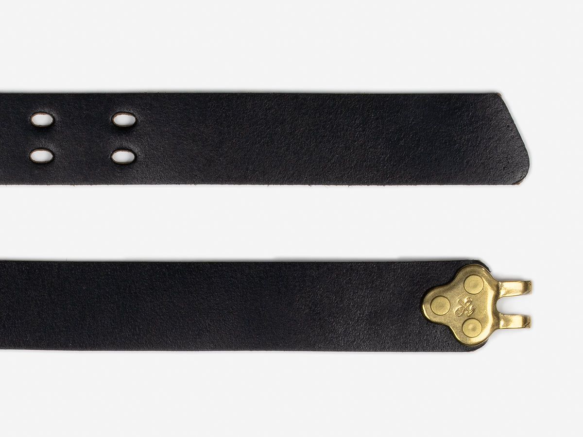 A close-up of a black leather belt featuring punched holes on one end and a brass key-shaped buckle on the other end, displayed against a white background.