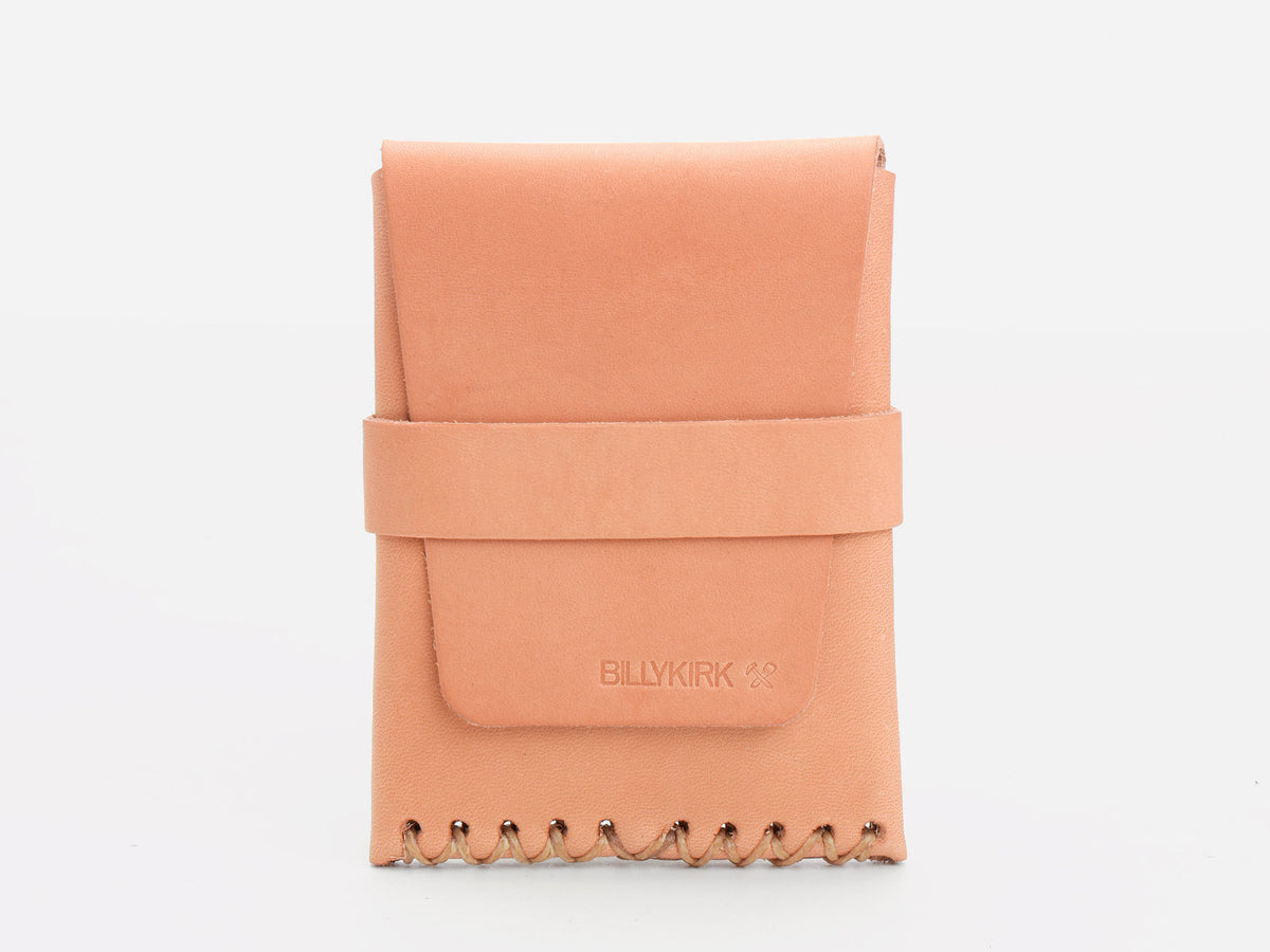 A natural colored leather card case with a flap closure, wide strap across the front, and decorative stitching along the bottom edge, placed against a plain white background.