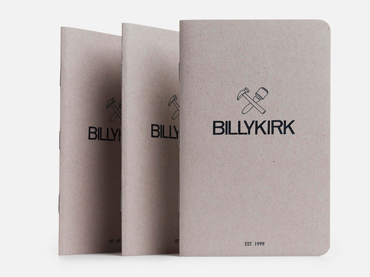 Three gray Billykirk notebooks stand upright in a row. Each has the Billykirk logo with a hammer and mallet above the brand name, and EST. 1999 printed at the bottom on a plain background.