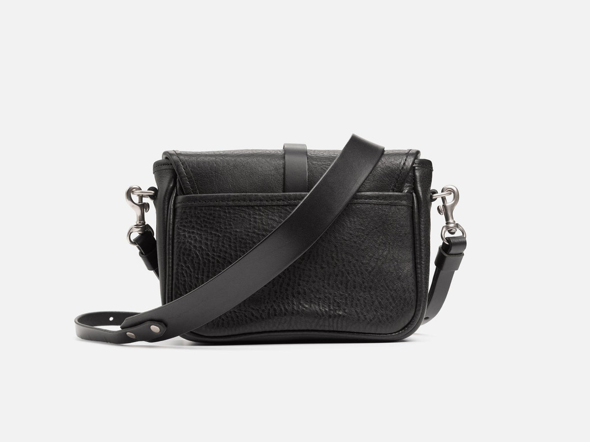A small black leather crossbody bag with a long adjustable strap, metal clasps, and a front flap pocket, displayed against a plain white background.