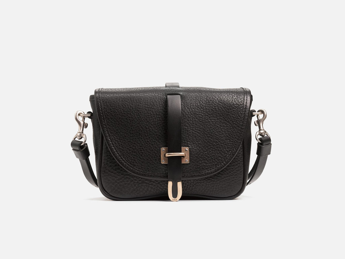 A black leather crossbody bag with a textured finish, front flap, silver hardware, and an adjustable shoulder strap, displayed against a plain white background.