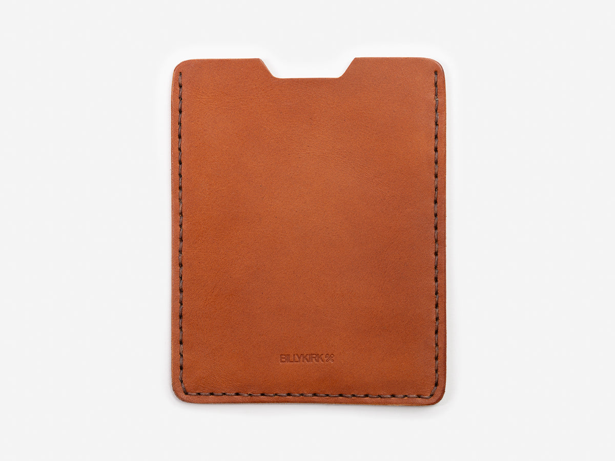 A minimalist brown leather card holder with visible stitching around the edges, featuring a semicircular notch at the top for easy access to cards. The brand name BILLYKIRK is embossed at the bottom center.
