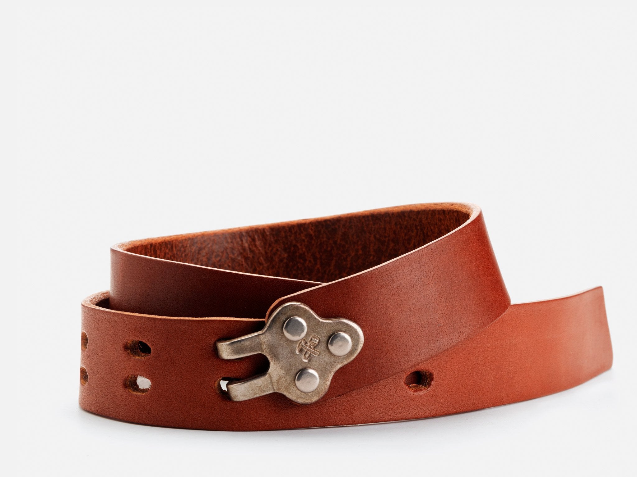 A coiled brown leather belt with a unique, rustic silver buckle featuring three rivets, displayed on a white background.